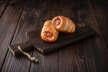 Sausage Rolls. Mini sausages in a bun on brown boards. For decoration of bakery sales outlets. Bakery products. Fresh bakery.