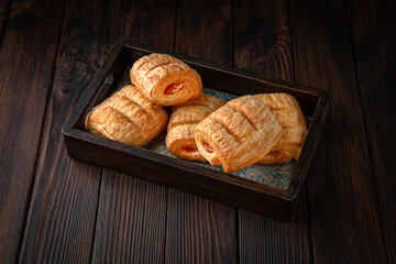 Bun from puff pastry with strawberry or cherry jam on brown boards. For decoration of bakery sales outlets. Bakery products. Fresh bakery.