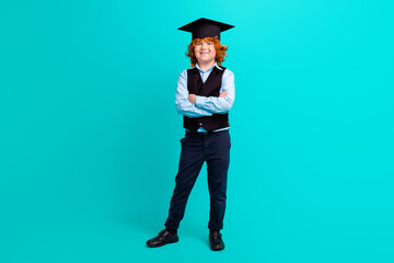 Full body portrait of positive clever schoolkid crossed arms posing wear mortarboard hat isolated on turquoise color background