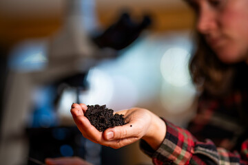 female scientist holding mineral soil in a laboratory