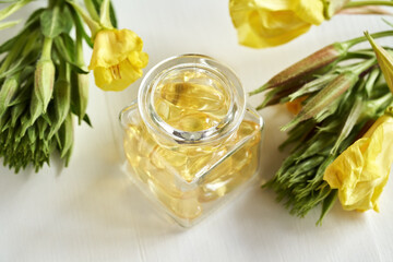 A glass bottle with evening primrose capsules on white background