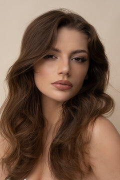 Studio shot of attractive young woman in brown sweater on brown background.
