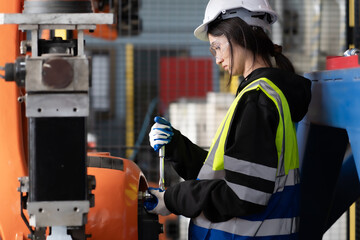 Maintenance engineer woman standing in mechanic factory using wrench to repair machine. Female service technician wears safety hardhat working in workshop fix machine with spanner key manual tool.