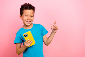 Photo portrait of сute little boy finger point up empty space telephone wear trendy blue clothes isolated on pink color background