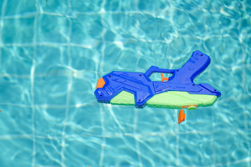Blue water gun floats in the pool. A toy for playing in the pool or on the beach