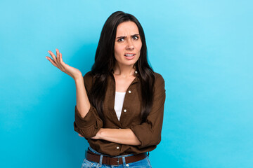 Photo of unsatisfied young woman wear brown shirt confused wtf misunderstanding irritated pretense isolated on blue color background