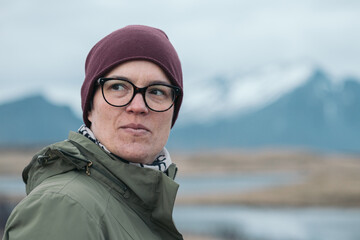 Portrait of Caucasian woman with glasses next to mountains in Iceland, family trip