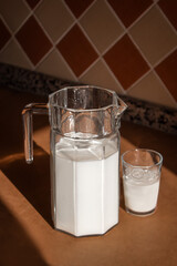 a glass jug with milk stands on a wooden table