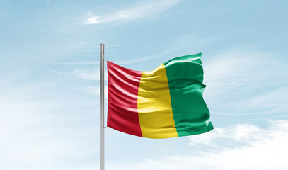 Guinea national flag waving in beautiful sky. The symbol of the state on wavy silk fabric.