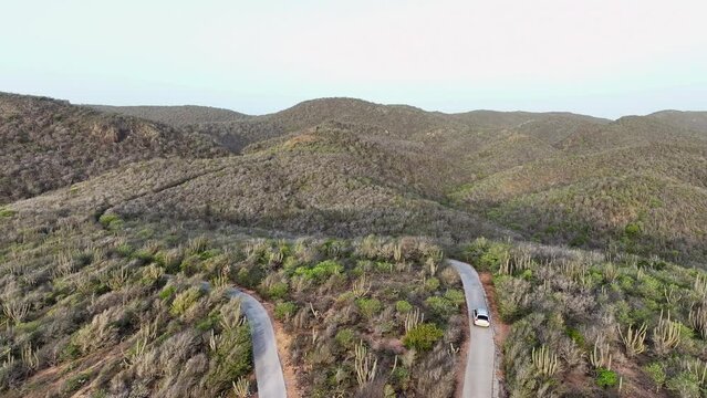 Aerial view of a car driving on a scenic mountain route on an island in the Caribbean