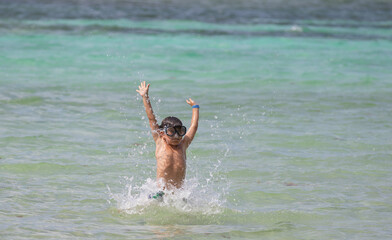 Beautiful little boy having fun in the water on a beach
