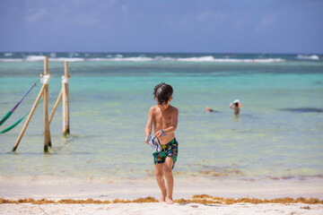Little beautiful boy coming out of the ocean on the beach