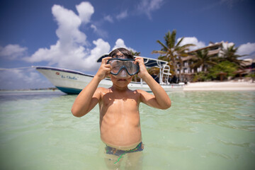 Beautiful little boy putting on mask for diving on a beach