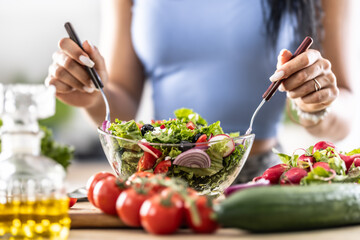 Female hands mixing a healthy spring salad made from various ingredients. Concept of healthy...