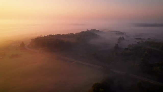 Morning haze fog panorama during beautiful orange sunrise - DJI Mavic drone flight above clouds at countyside near fields and nordic forest