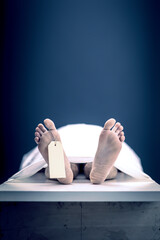 feet with dead man's tag in mortuary background