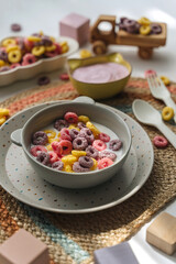 Colorful cereal rings with milk in bowl. Dry children's breakfast. Cute children's plates and bowls with tasty food. Creative serving for baby. Concept of kids menu, nutrition and feeding.