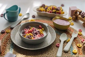 Dry children's breakfast. Cute children's plates and bowl with colorful cereal rings of milk....