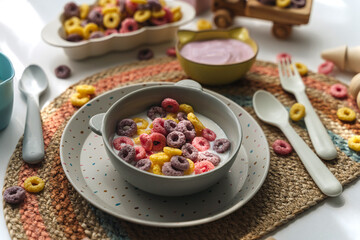 Colorful cereal rings with milk in bowl. Dry children's breakfast. Cute children's plates and bowls with tasty food. Creative serving for baby. Concept of kids menu, nutrition and feeding.