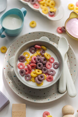 Colorful cereal rings with milk in bowl. Dry children's breakfast. Cute children's plates and bowls with tasty food. Creative serving for baby. Concept of kids menu, nutrition and feeding.