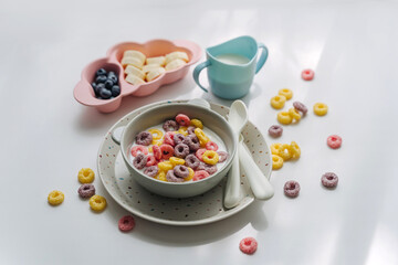 Dry children's breakfast. Cute children's plates and bowl with colorful cereal rings of milk. Creative serving for baby.  Concept of kids menu, nutrition and feeding.