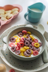 Colorful cereal rings with milk in bowl. Dry children's breakfast. Cute children's plates and bowls with tasty food. Creative serving for baby. Concept of kids menu, nutrition and feeding.