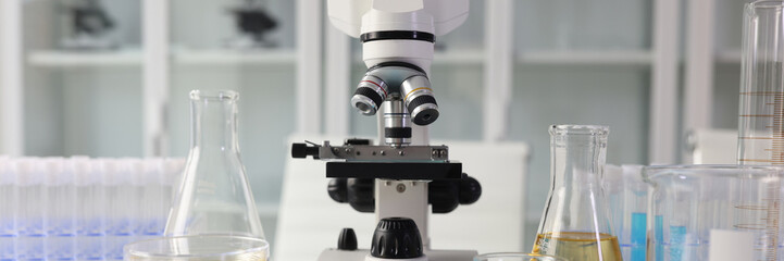 Fototapeta na wymiar Microscope and chemical laboratory glassware on lab table.