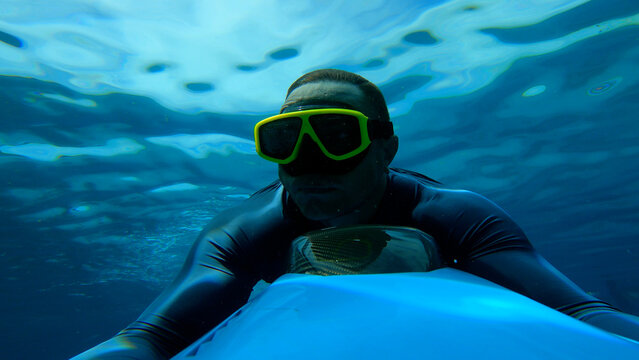 A man swims underwater with an underwater scooter, a man in the sea rides underwater on an underwater scooter