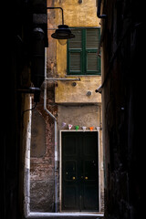 view of an old facade through one narrow street in Genoa Italy