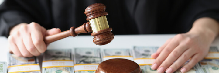 Judge with wooden gavel and a lot of dollar bills close-up.
