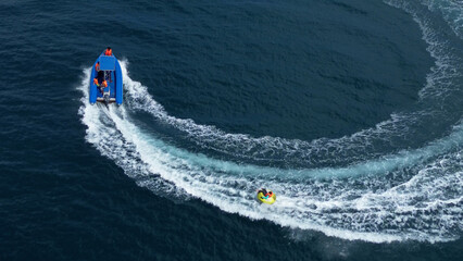 Riding an inflatable donut behind a fast boat, riding an inflatable ring on the sea, drone view