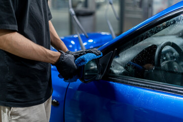 person wipes car body with car microfiber at car wash