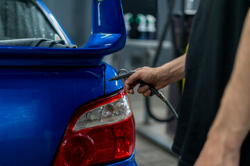 a man at a car wash uses an air compressor to dry a car