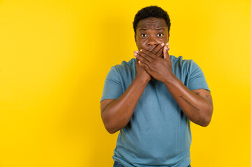 Young handsome man standing over yellow studio background shocked covering mouth with hands for...