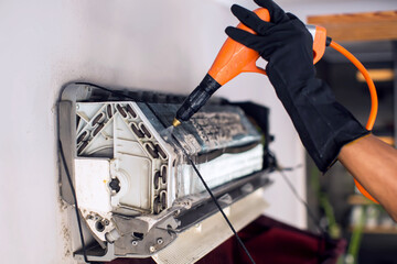  Cleaning the air conditioner by spraying. man washes off a special foam for cleaning air...