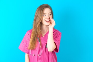 beautiful doctor woman standing over blue studio background  hear incredible private news impressed...