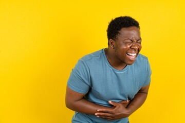 Young handsome man standing over yellow studio background smiling and laughing hard out loud because funny crazy joke with hands on body. - obrazy, fototapety, plakaty