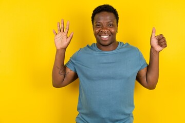 MODEL showing and pointing up with fingers number six while smiling confident and happy.