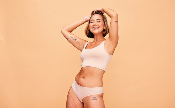 Happy, lingerie and body of woman in studio isolated on a brown background mockup space. Smile, underwear and model in natural beauty, self love and confidence for positivity, health and wellness