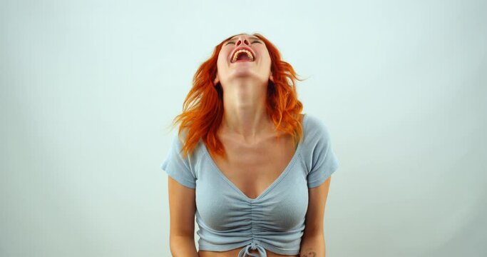 Moments when a red-haired girl looks at the camera in slow motion and laughs sincerely in a studio environment