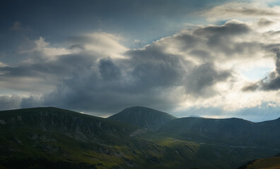 Fototapeta premium Sunset over Transalpina waving curved road in Romania. Beautiful landscape from Parang mountains during a spectacular summer sunset view. Travel to Transylvania.