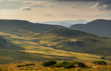 Fototapeta premium Sunset over Transalpina waving curved road in Romania. Beautiful landscape from Parang mountains during a spectacular summer sunset view. Travel to Transylvania.