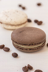French creamy macaroons in white and brown tone on white background, coffee beans and macarons. Macro