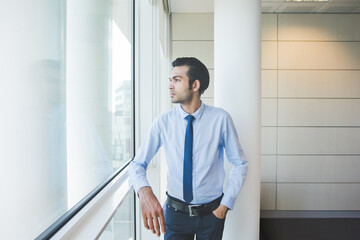 Fototapeta premium Young millennial businessman posing indoors office reassuring