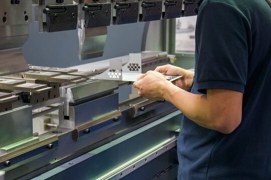Close up the bending machine operator hold the sheet metal parts.