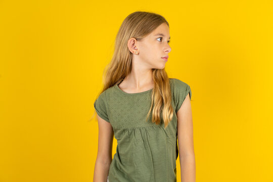 Close up side profile photo Beautiful caucasian kid girl wearing green dress not smiling attentive listen concentrated