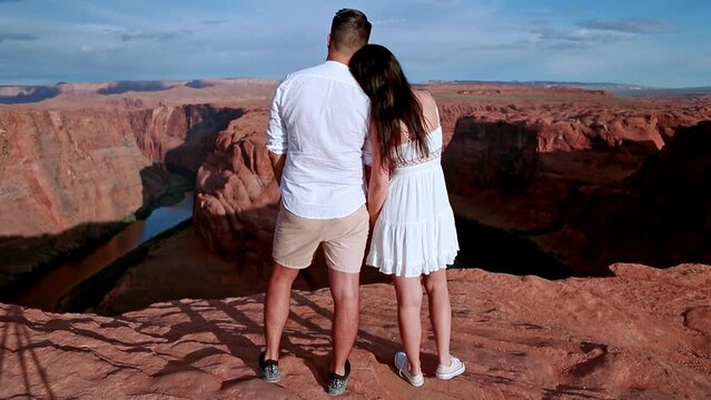 Happy couple on the edge of the cliff at Horseshoe Band Canyon in Paje, Arizona. Adventure and tourism concept. Beautiful nature in USA