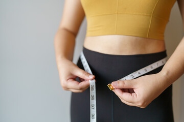 woman want to lose weight with a centimeter Shape up healthy stomach muscle and diet measuring waist with measure tape after diet weight control - obrazy, fototapety, plakaty