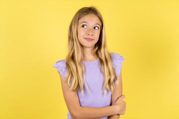 Pleased Beautiful caucasian kid girl wearing violet dress keeps hands crossed over chest looks...