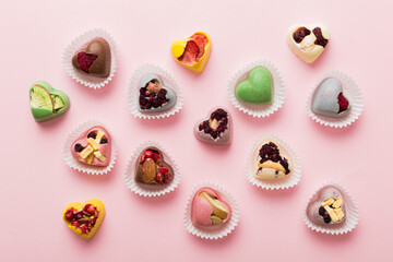 chocolate sweets in the form of a heart with fruits and nuts on a colored background. top view with space for text, holiday concept